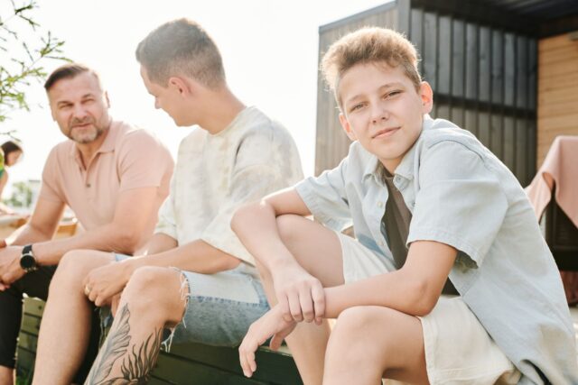 Un adult își ajută fiul adolescent să construiască ceva, într-un spațiu de lucru amenajat